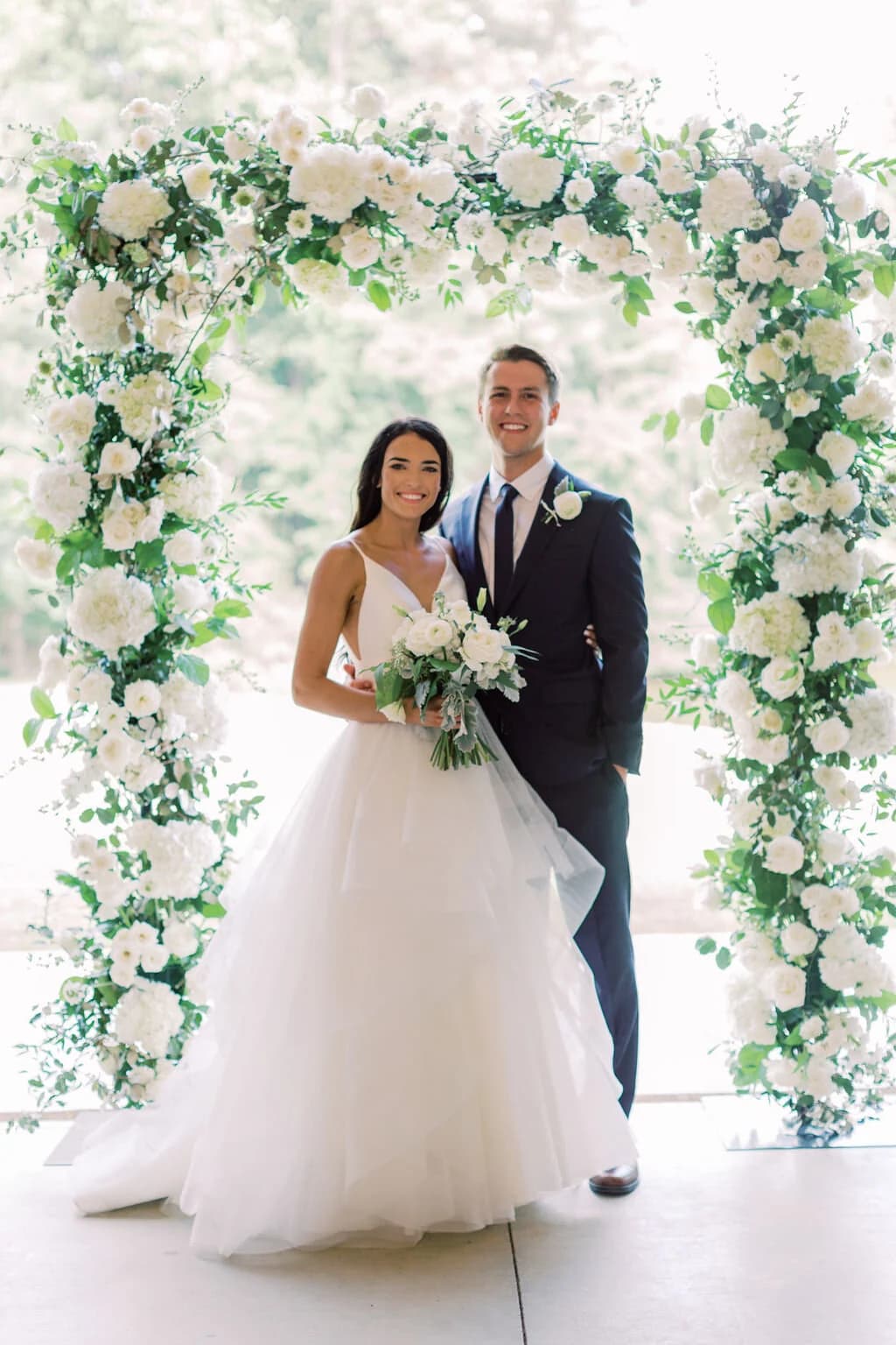 A couple beneath a white floral arch