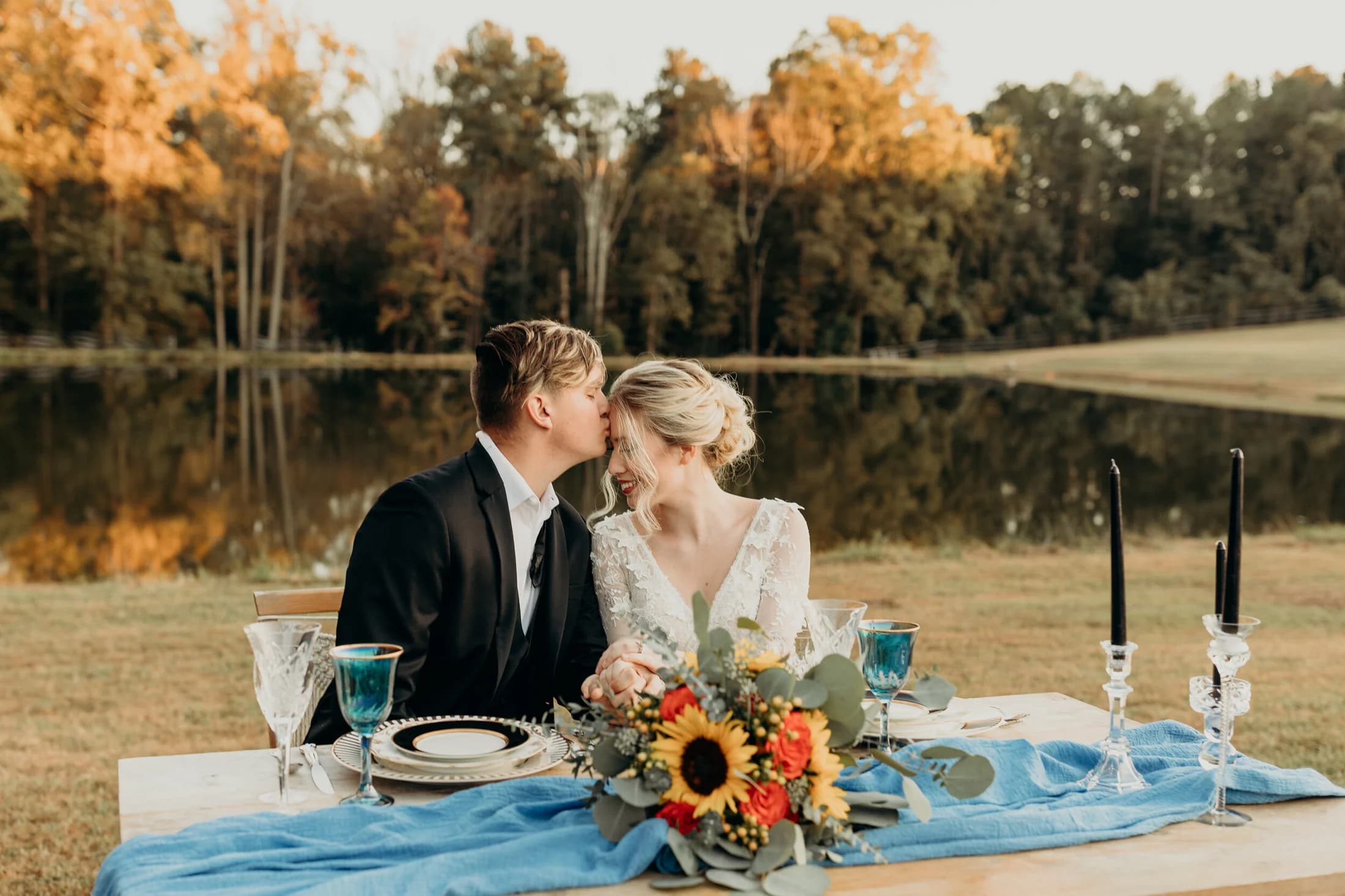 A couple at a candlelit table by the lake at sunset