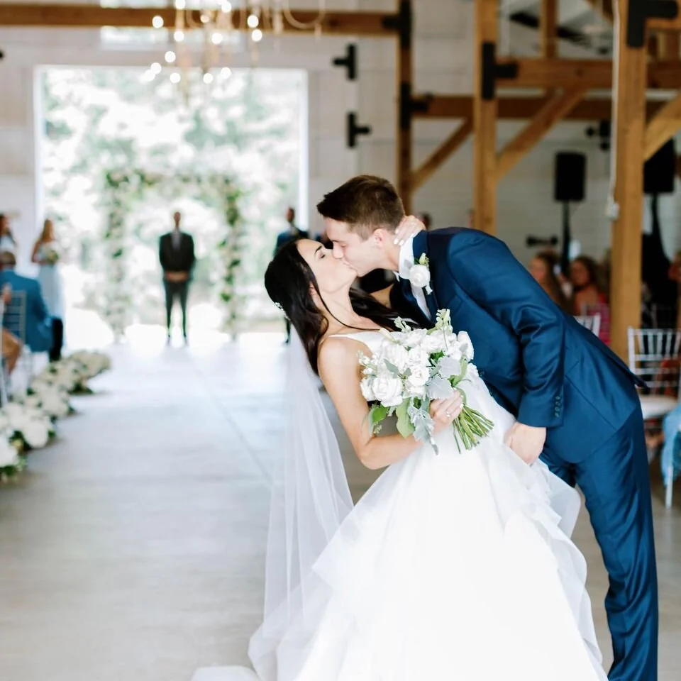 Newlyweds share their first kiss in the barn aisle