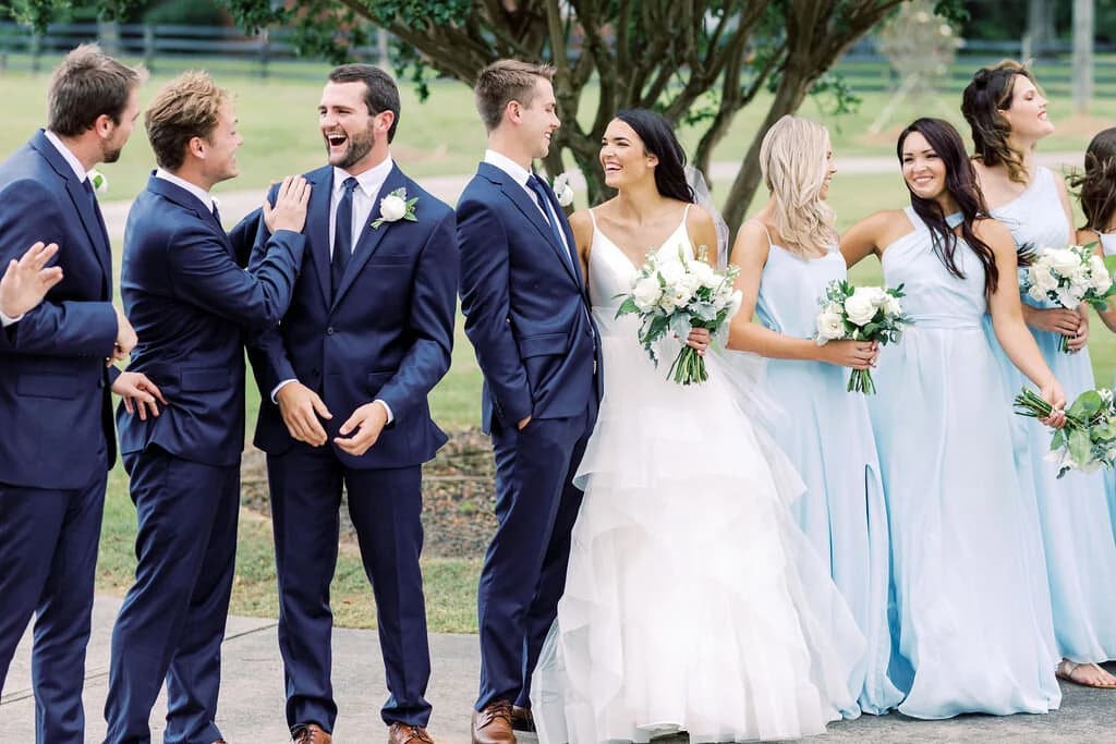 A wedding party laughing together on the lawn